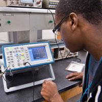 Student adjusting electronics equipment